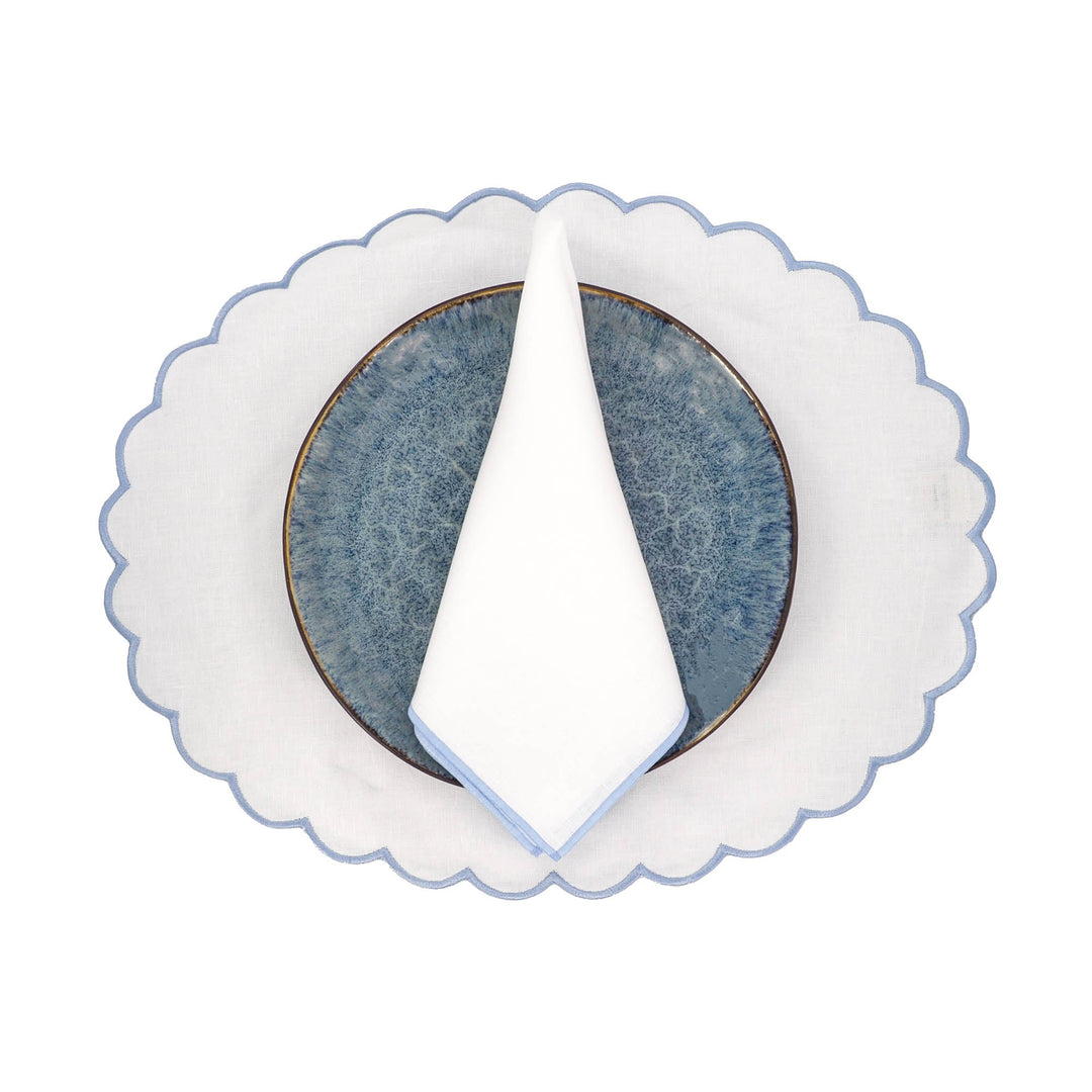 Linen napkin folded into a triangle with blue stitched edge on a plate