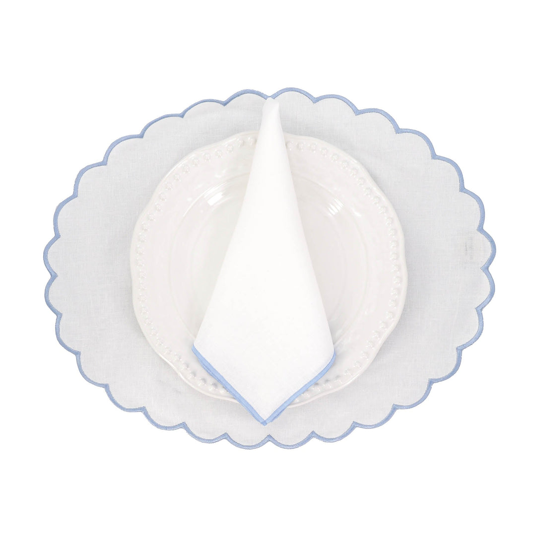 Linen napkin folded into a triangle with blue stitched edge on a plate