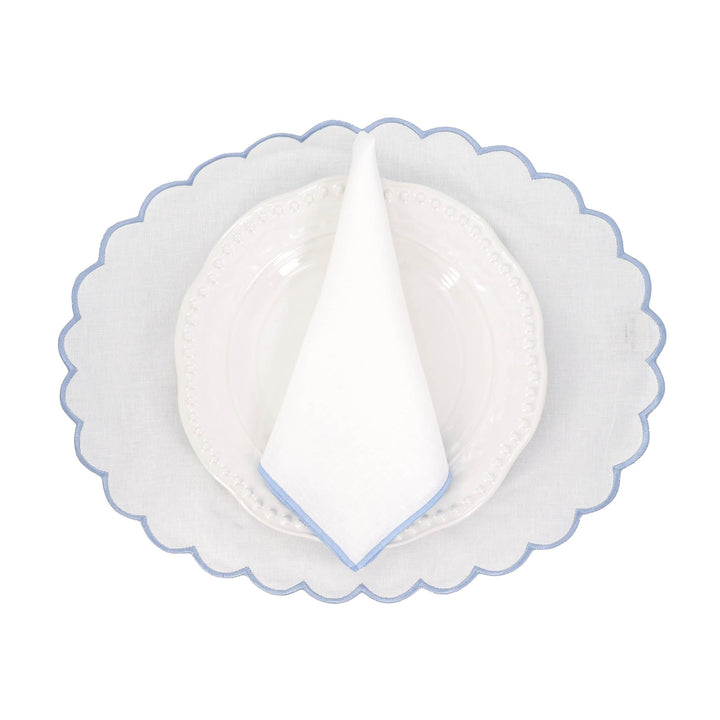Linen napkin folded into a triangle with blue stitched edge on a plate