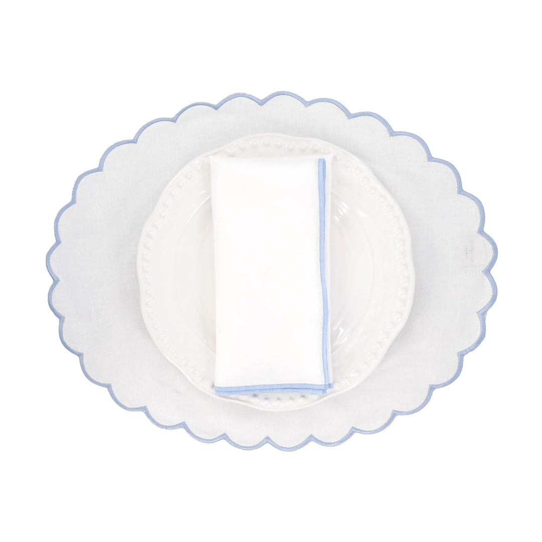 White linen napkin with blue stitched edge folded flat on a plate
