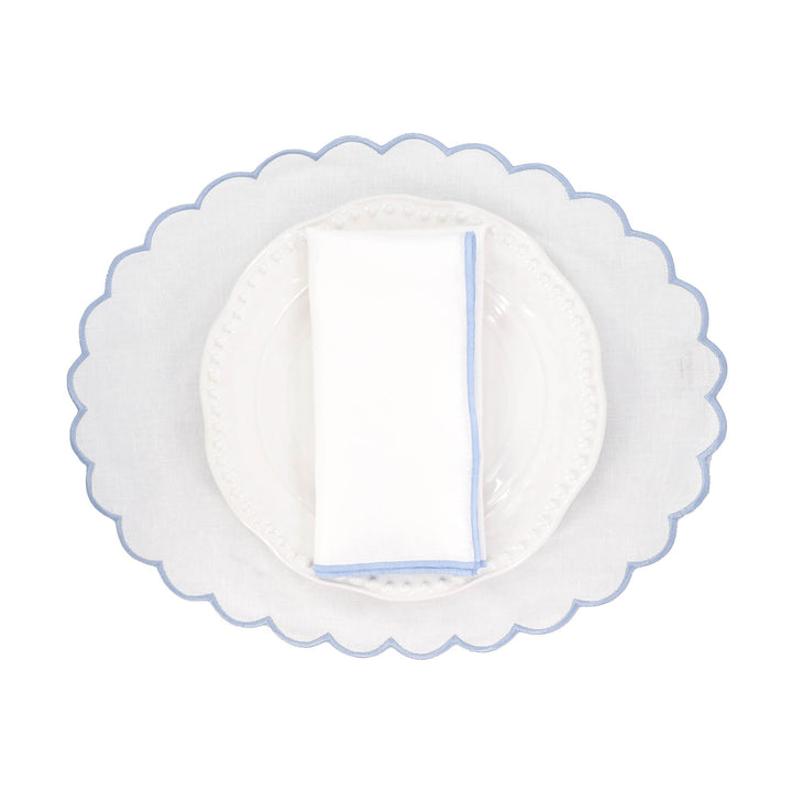 White linen napkin with blue stitched edge folded flat on a plate