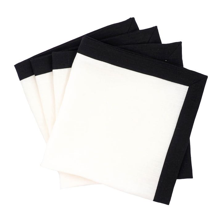 Linen napkins set of four with white center and black border, stacked.