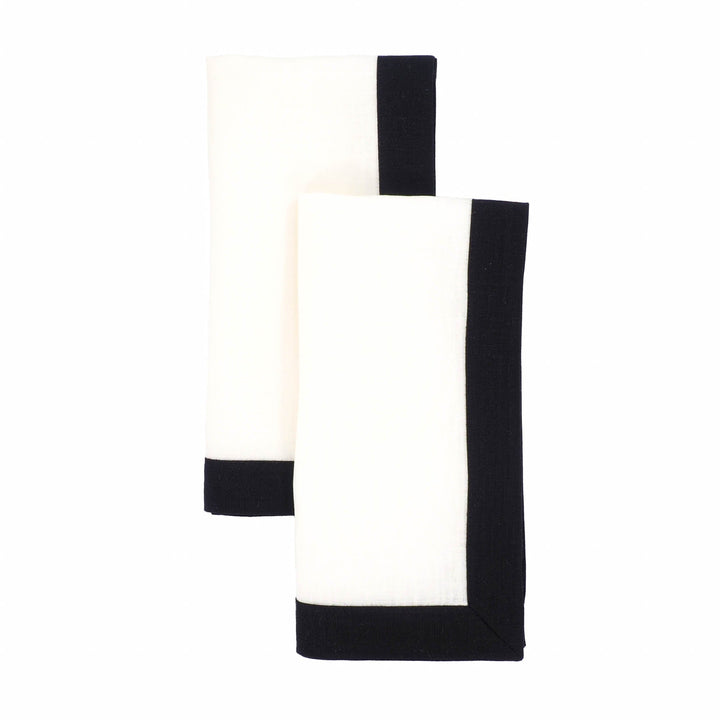 Set of two folded linen napkins with white fabric and black border panels.