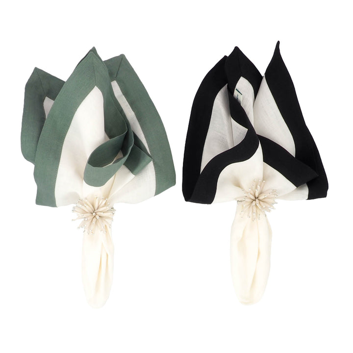 Folded linen napkin with white center and black border, tied with flower detail.