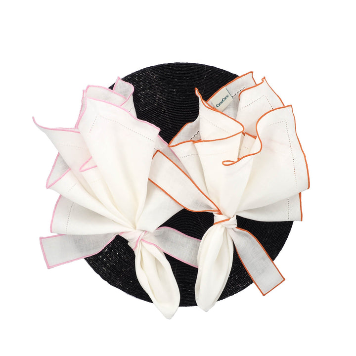Set of 4 white linen napkins with orange ruffled hemstitch edges, tied folded bundle