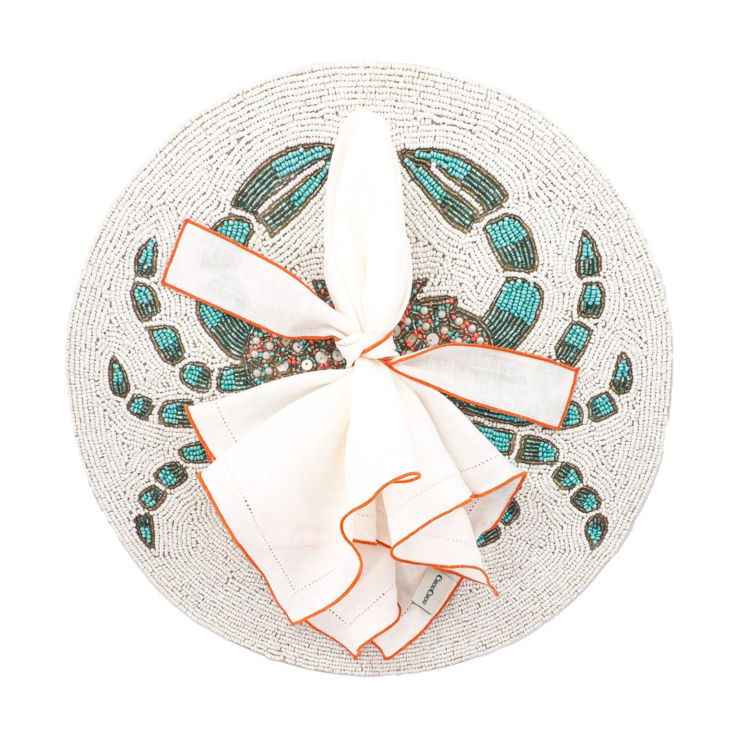 White linen napkins bundle with orange ruffled hemstitch edges, folded and tied