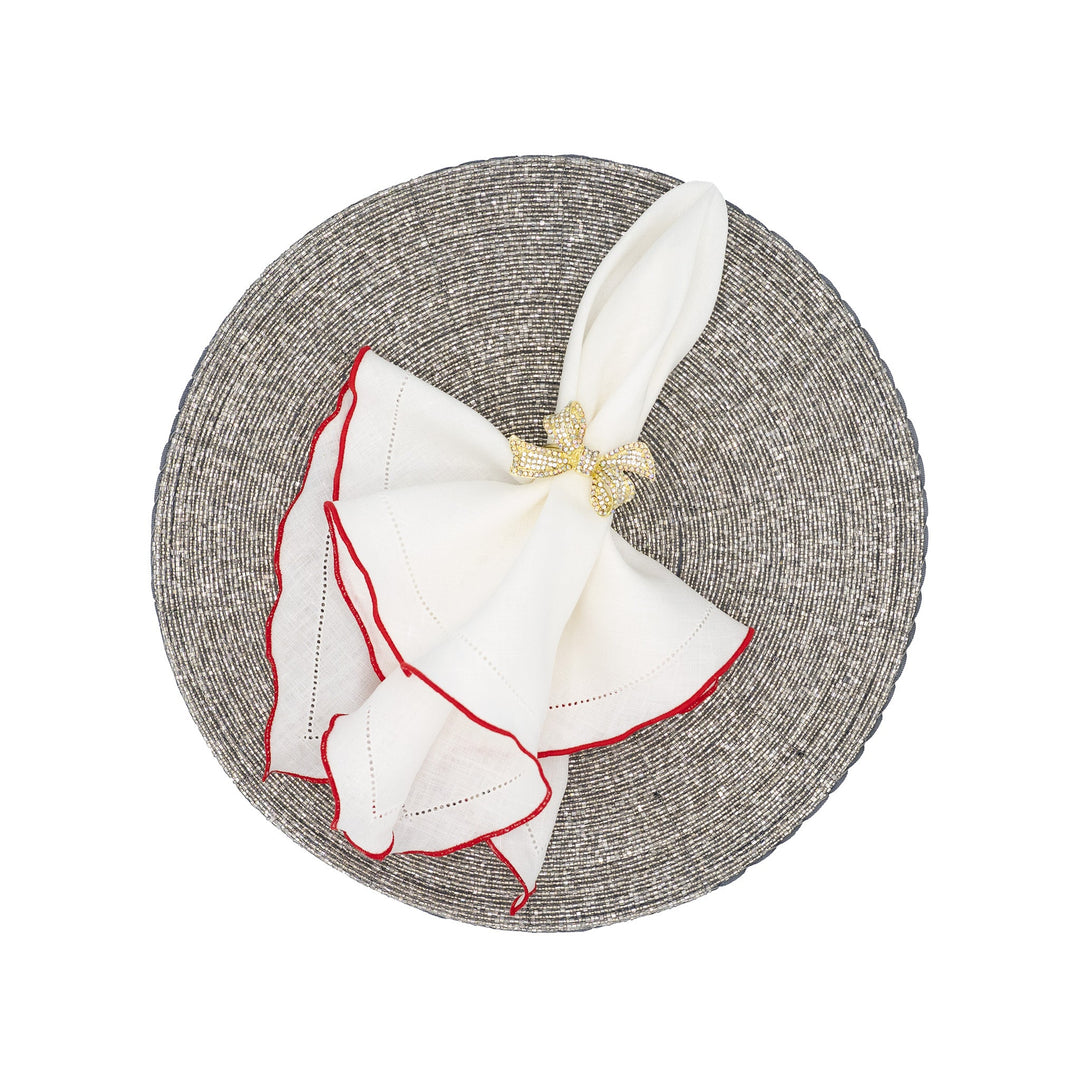 White linen napkins with red ruffled hemstitch edges, folded with gold bow tie