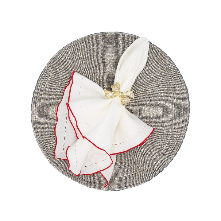 White linen napkins with red ruffled hemstitch edges, folded with gold bow tie