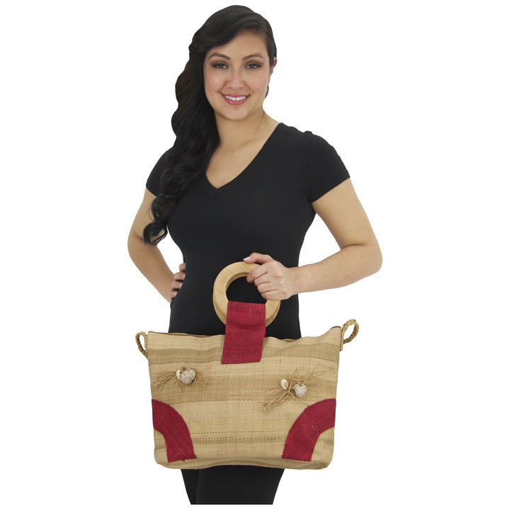 Raffia tote bag with red accents and rope handles, carried on a model.