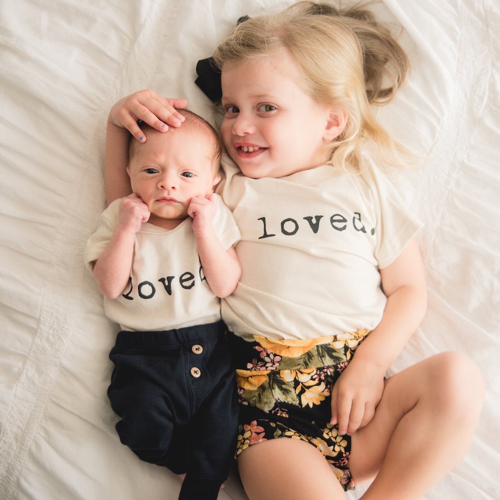 Kids organic T-shirt with “loved.” print, worn with dark shorts