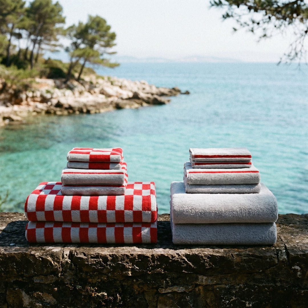 Cotton towels showing red-and-white checker towel and gray rolled terry towels
