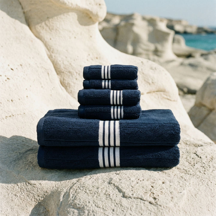 Folded set of dark navy cotton bath towels with white striped bands