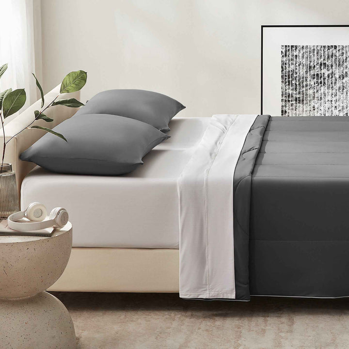 Gray cooling comforter set on bed with white base sheet and dark trim