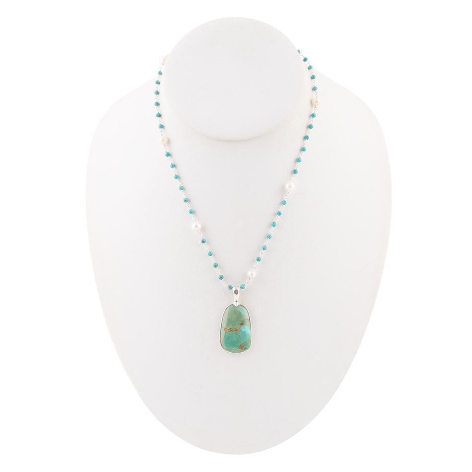 Turquoise beaded drop pendant necklace with small oval pendant on mannequin bust