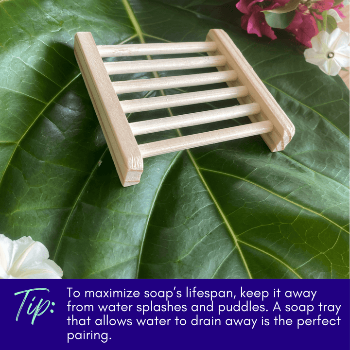 Wooden soap tray with slatted design on green leaves