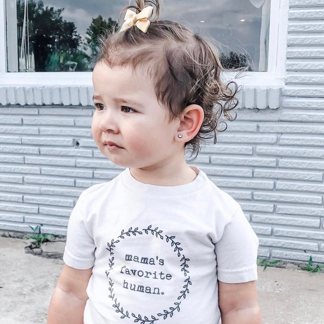 Kids organic cotton T-shirt in white with wreath graphic and “mama’s favorite human” text