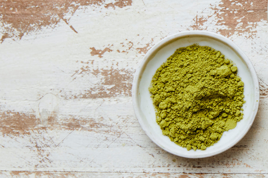 Culinary matcha powder in white bowl on rustic surface