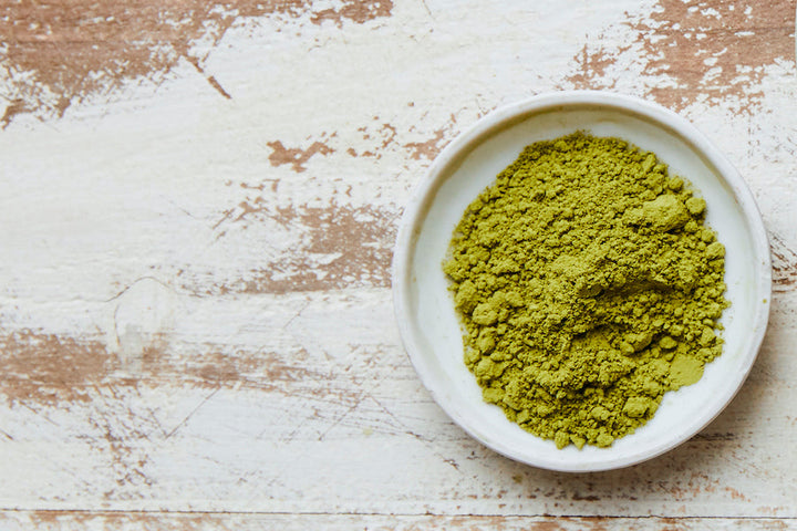 Culinary matcha powder in white bowl on rustic surface