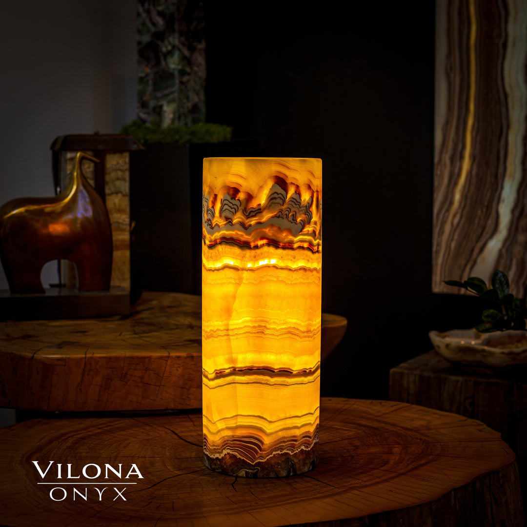 Onyx cylinder table lamp with warm amber light through banded stone interior