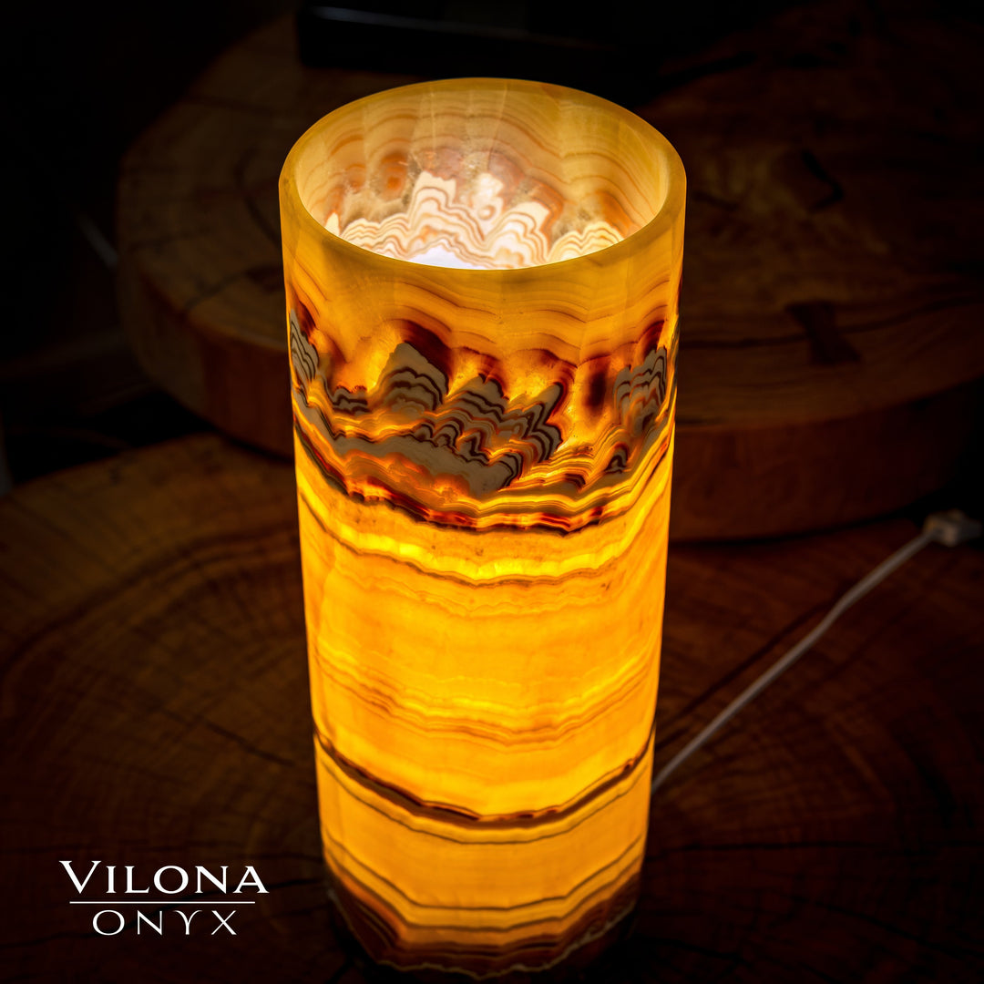 Onyx cylinder table lamp lit from inside, orange glow through banded onyx
