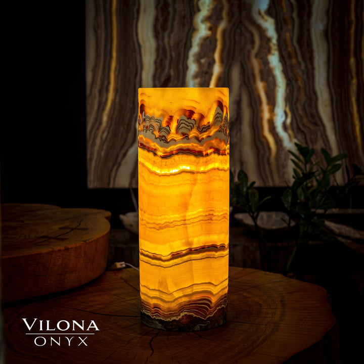 Onyx cylinder table lamp with warm amber glow and wavy stone pattern
