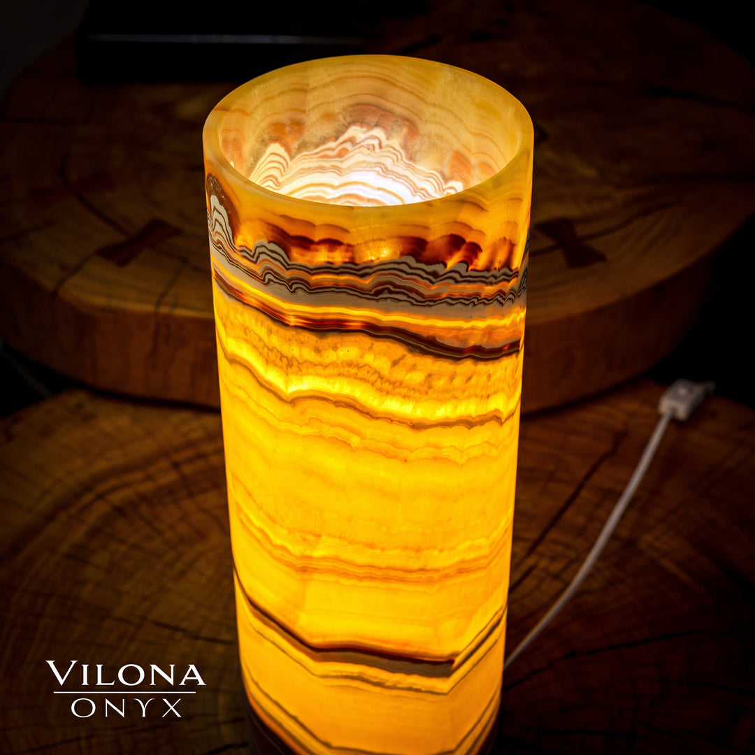 Onyx cylinder table lamp showing lit circular top opening and amber striped pattern