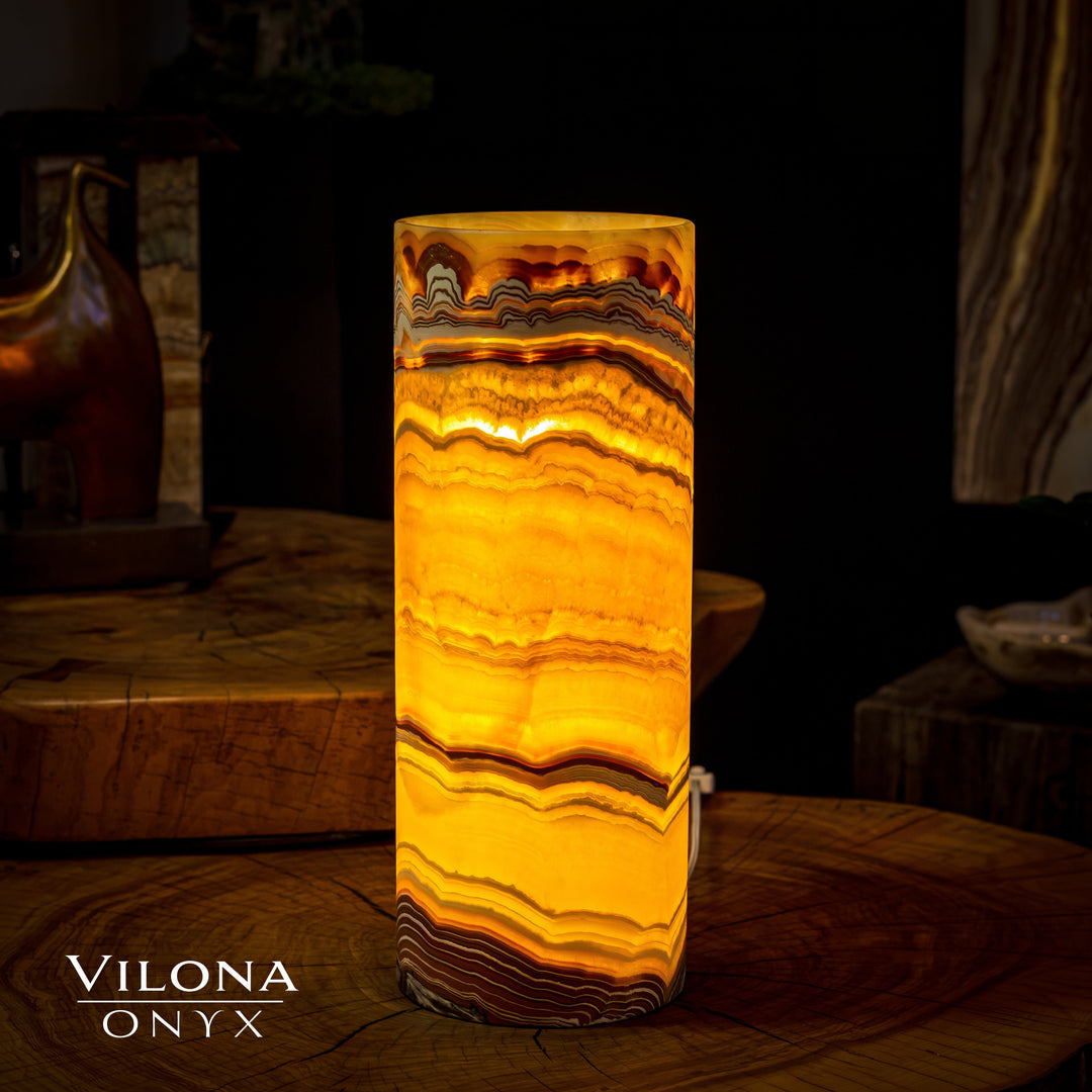 Onyx cylinder table lamp glowing amber with layered wavy stone pattern