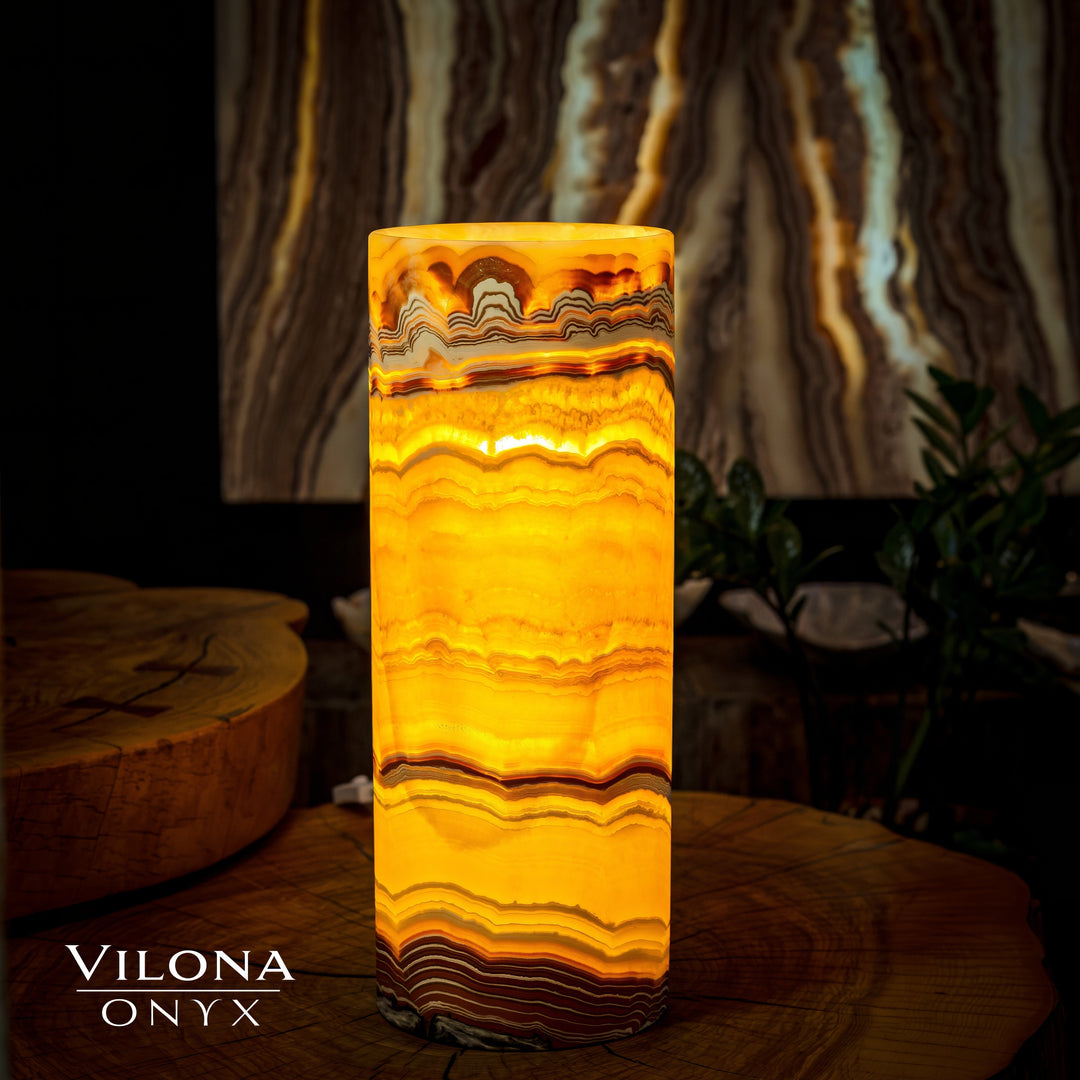 Onyx cylinder table lamp with warm amber glow and wavy striped stone body