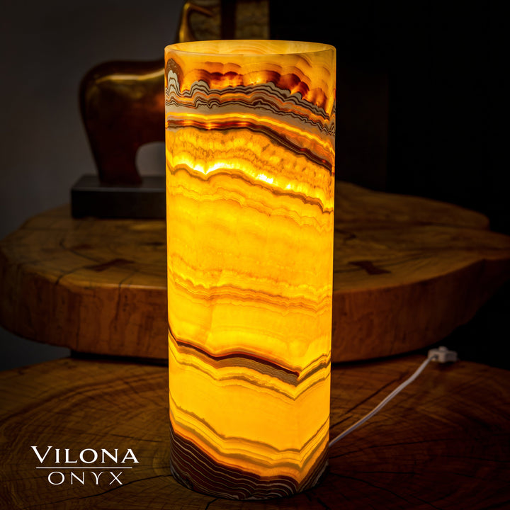 Onyx cylinder table lamp with glowing amber stripes and visible power cord