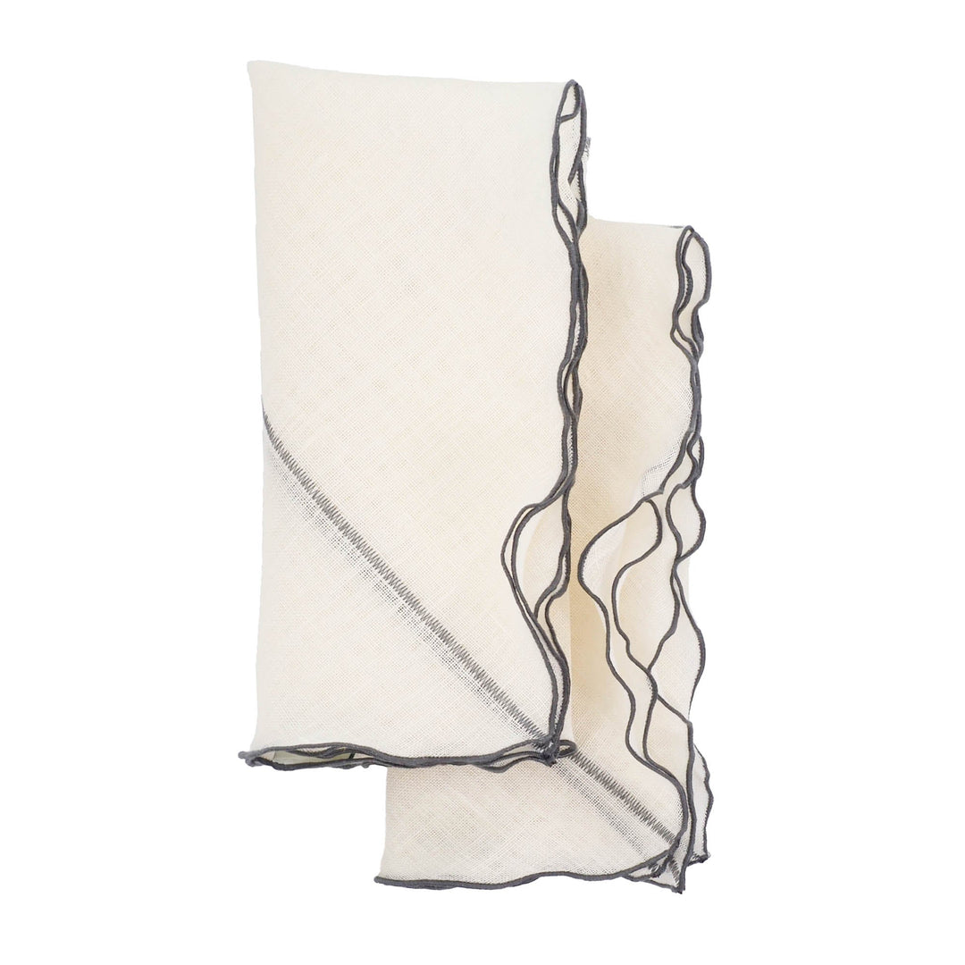 Off-white linen napkin with charcoal ruffled edges, stacked with a fold