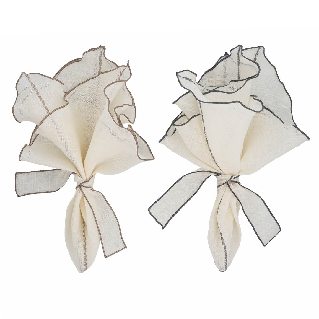Two off-white linen napkins tied into bows with charcoal ruffled trim