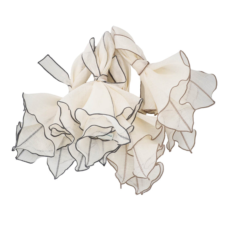 Folded off-white linen napkin with charcoal ruffled edges, shown in a pile