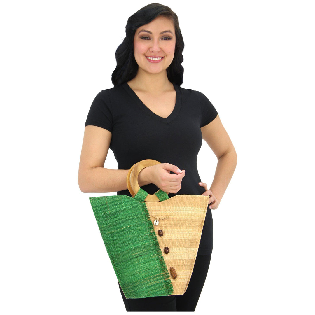 Green and tan raffia tote bag with wooden ring handle, held by model