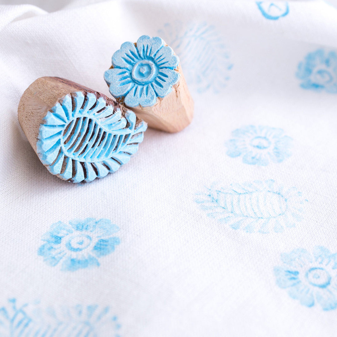 Wooden block stamps creating light blue flower and mandala prints on fabric