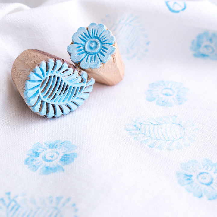 Wooden block stamps creating light blue flower and mandala prints on fabric