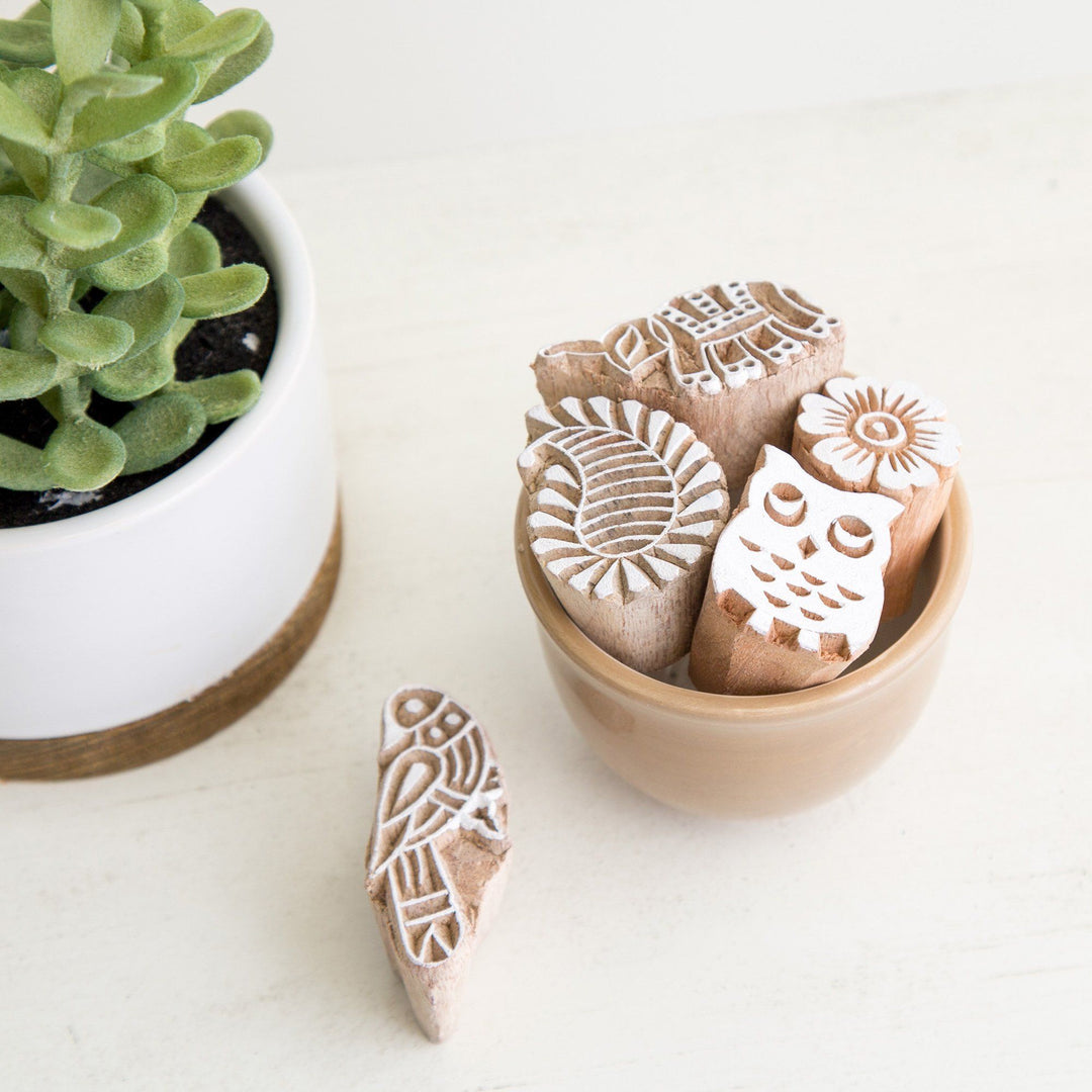 Wood block print stamp set with assorted animal and floral designs in a bowl