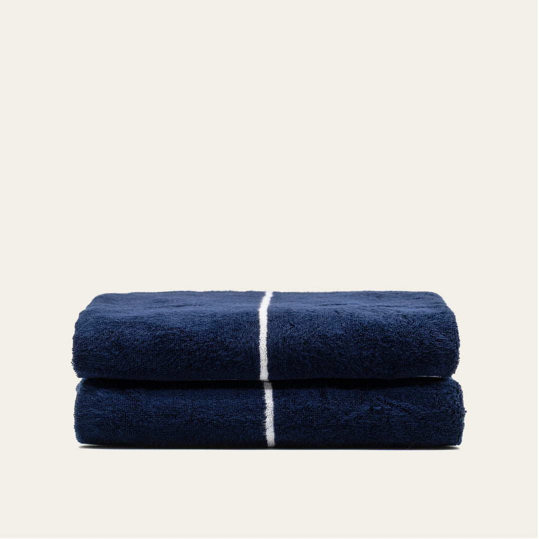 Navy and white cotton towels, two folded bath-size towels stacked with stripe bands.