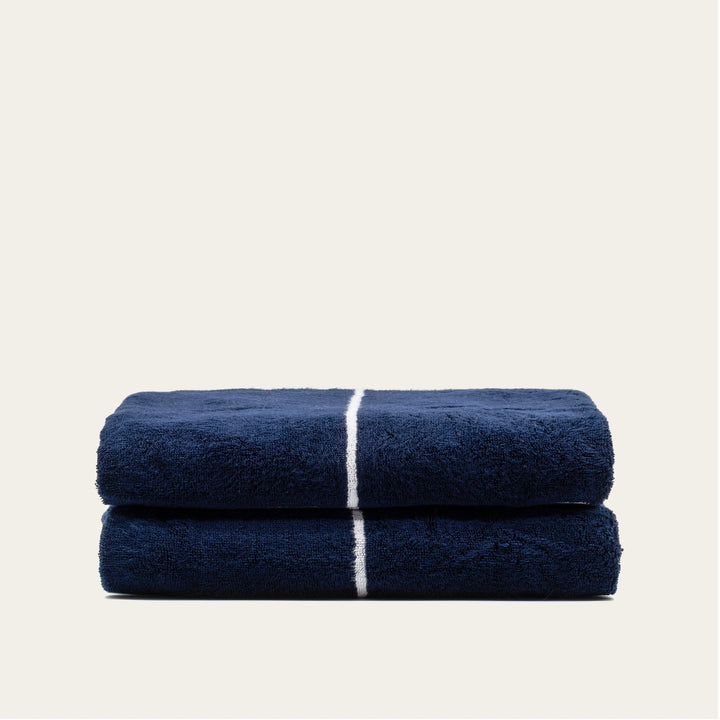 Navy and white cotton towels, two folded bath-size towels stacked with stripe bands.