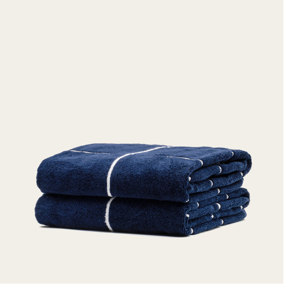 Folded navy cotton towel with white stripe across the roll