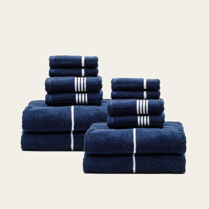 Grouped folded navy cotton towels with white stripe bands