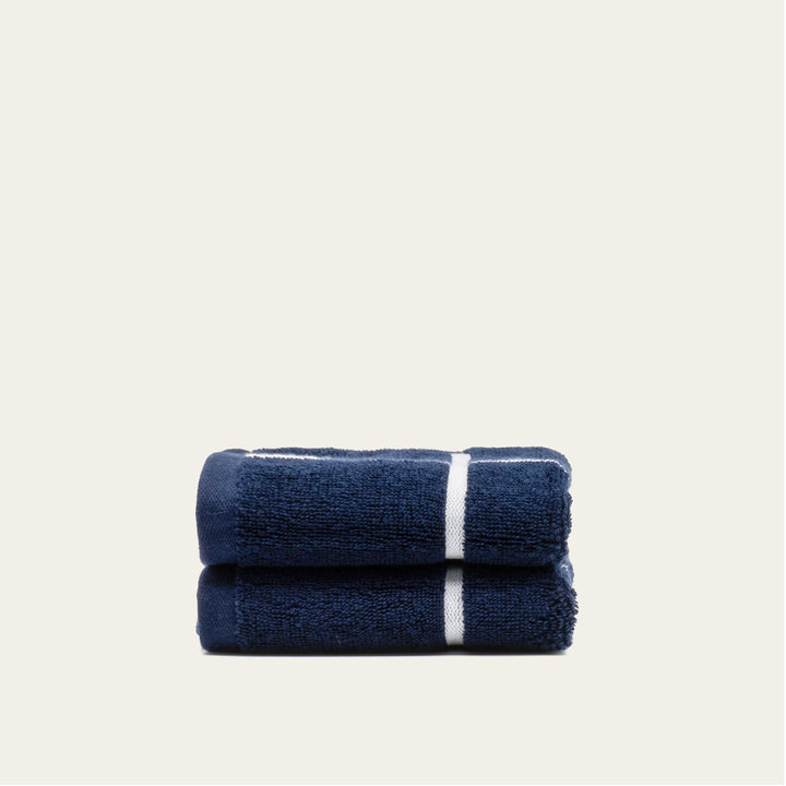 Navy and white cotton towel set, two folded towels with a central white stripe.