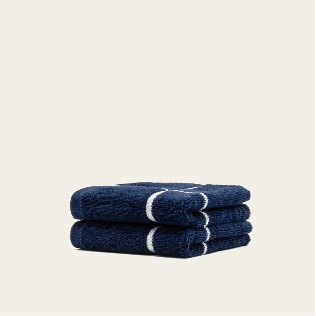 Navy and white cotton towels set, three folded towels stacked with white stripe accents.