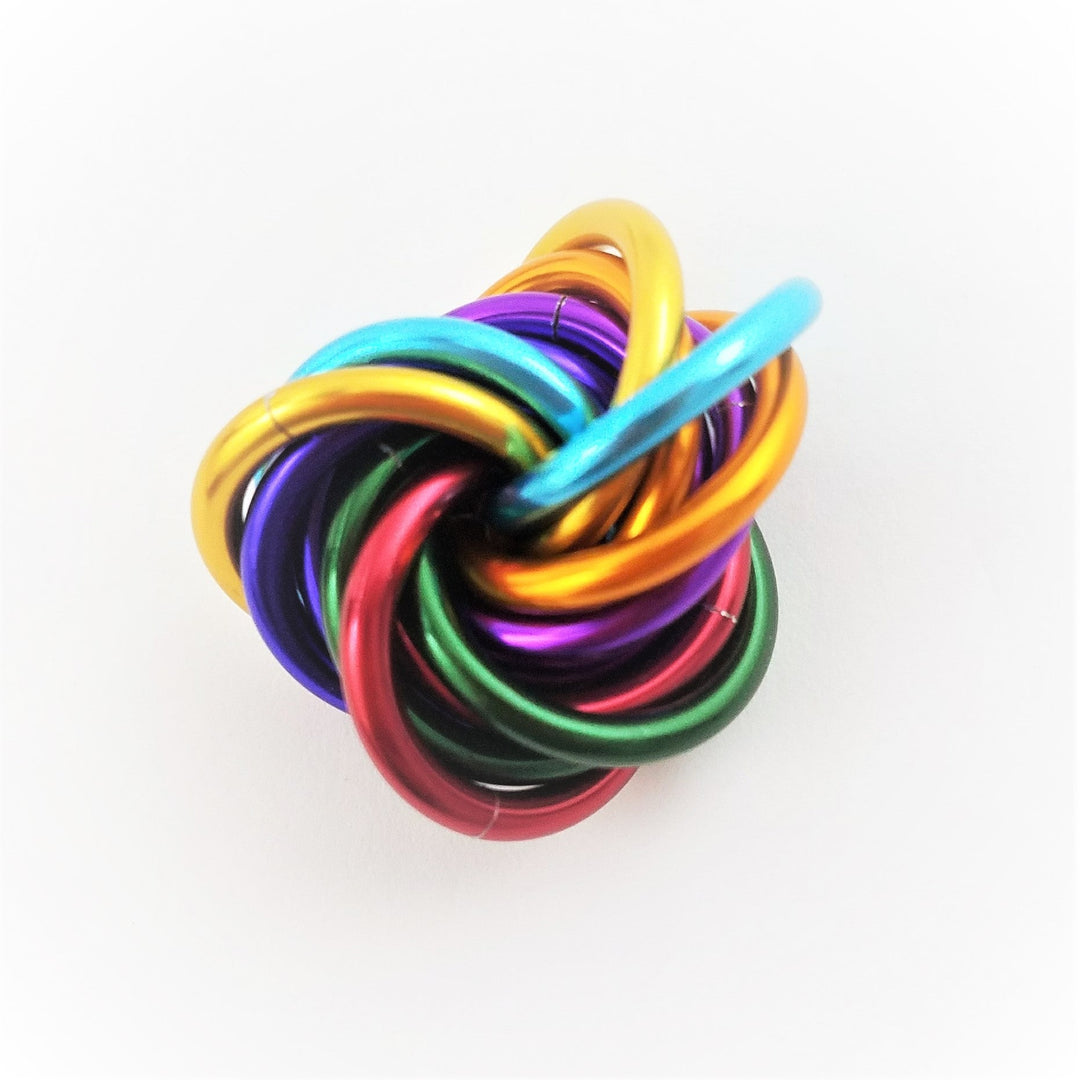 Shiny multicolor fidget stress ball knot with glossy rainbow rings, centered view.