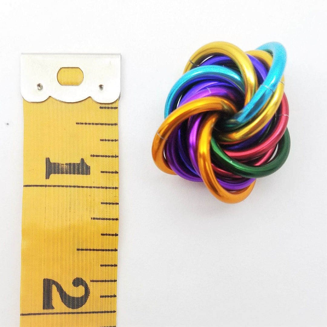 Shiny multicolor fidget stress ball with interlocking rainbow rings, close-up angle.