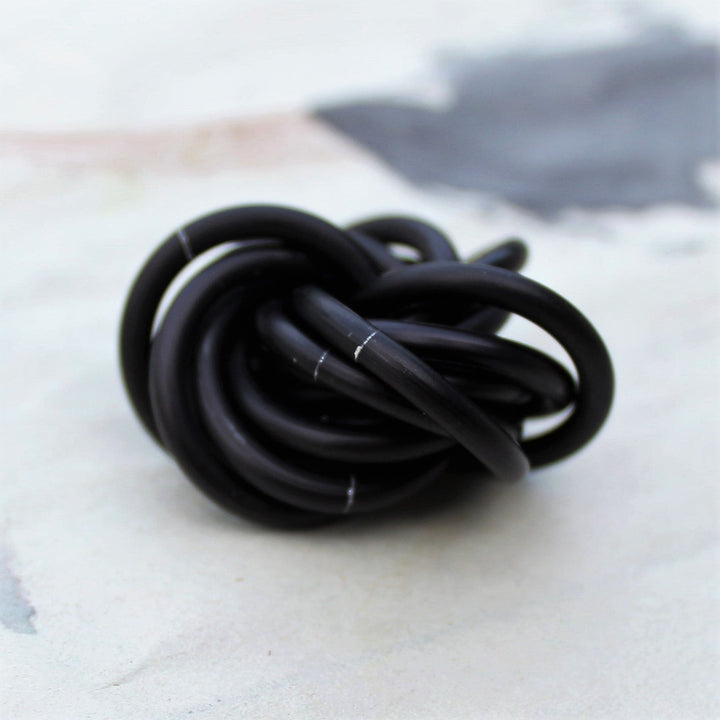 Black stress fidget ball with a glossy twisted knot loop design.