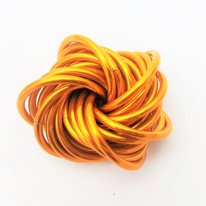 Orange metallic stress ball fidget toy with a twisted spiral coil