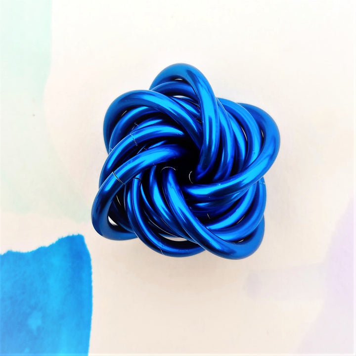 Blue metallic twist fidget stress ball with reflective sheen, knotted loop desk toy.