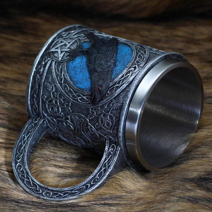 Stainless steel mug with raven relief panel, blue highlights, thick arched handle.