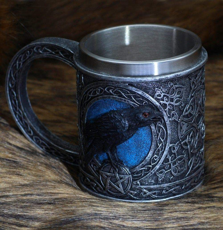 Stainless steel mug with raven relief side art, blue eye accents, arched handle.