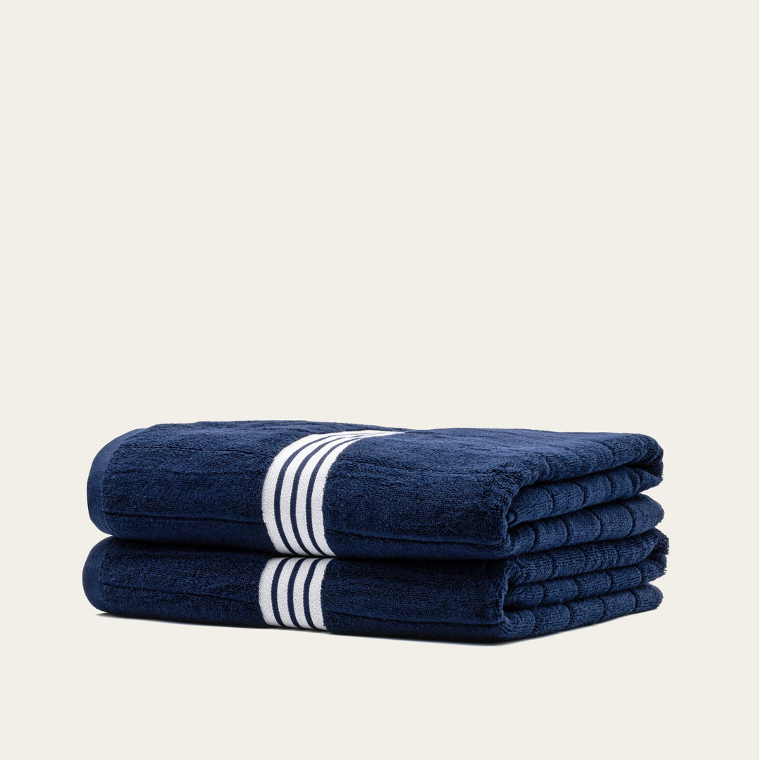 Navy cotton towel set with white striped bands, folded stack of 4 towels